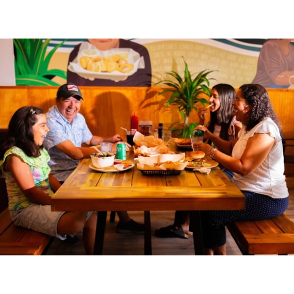 A family of four laughing and enjoying fish and chips at Kiwi Style Fish and Chips.