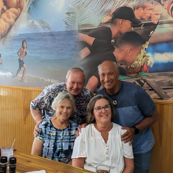 Four smiling customers, two men and two women, pose together at a table in Kiwi Style Fish and Chips.